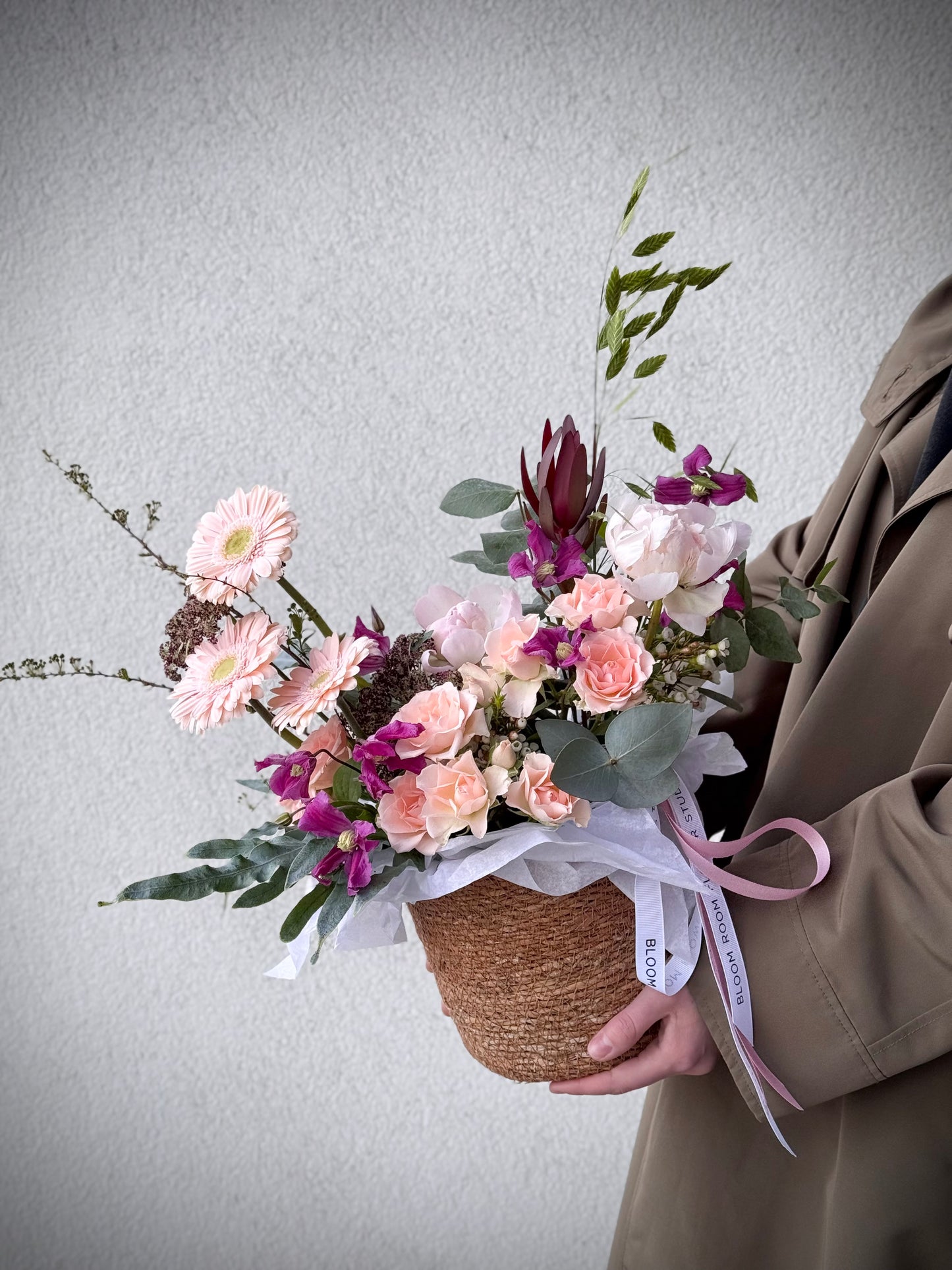 Signature flower arrangement in soft peach and blush tones, featuring spray roses, gerberas, eucalyptus, and seasonal blooms. A bubbly mix of elegance and cheer — like your favorite glass of prosecco in flower form. Comes in a natural basket with branded ribbon and care card.