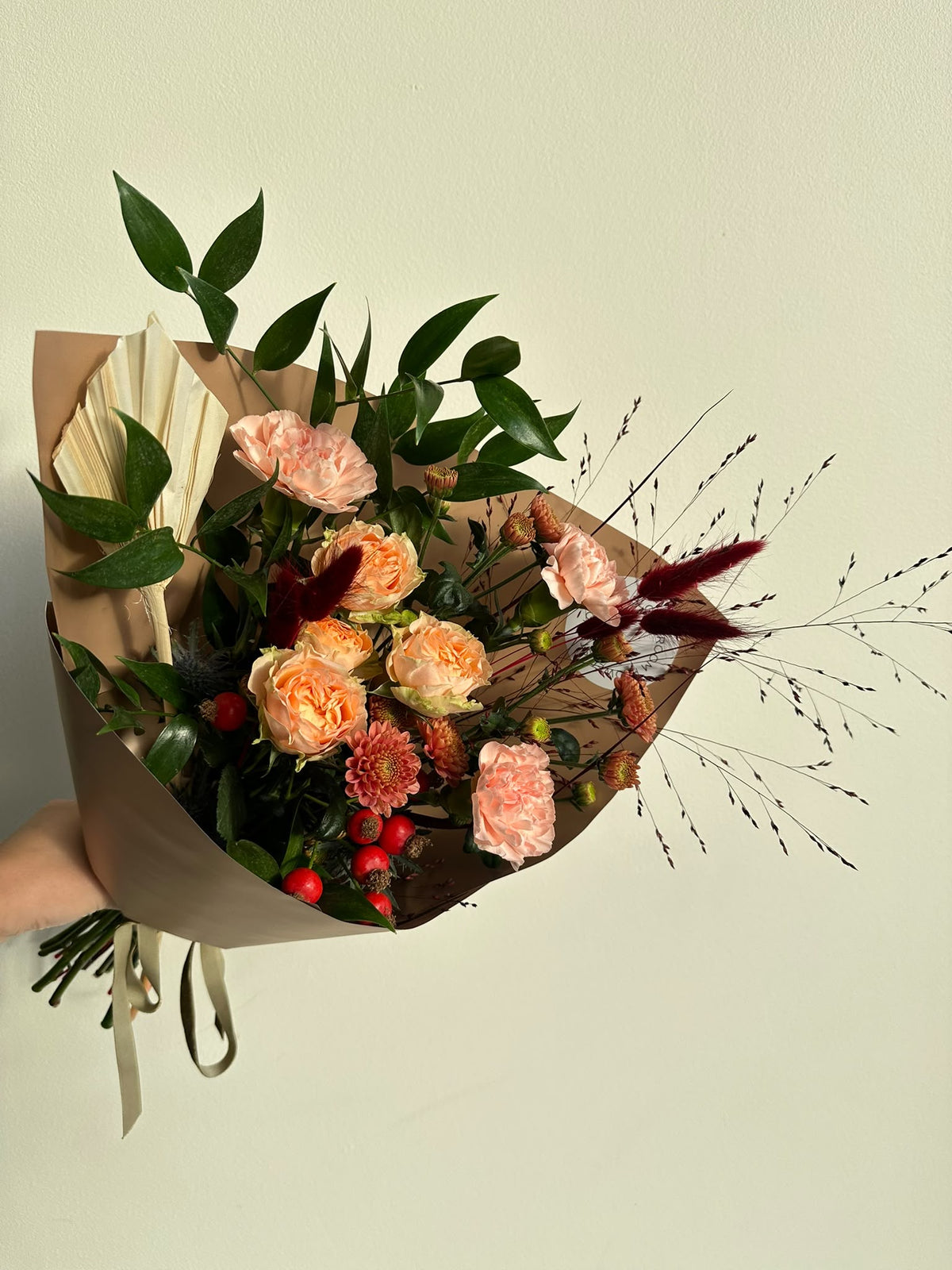 “Autumn Whisper” art bouquet with peach spray roses, carnations, copper chrysanthemums, rose hips and burgundy bunny tails in caramel wrapping