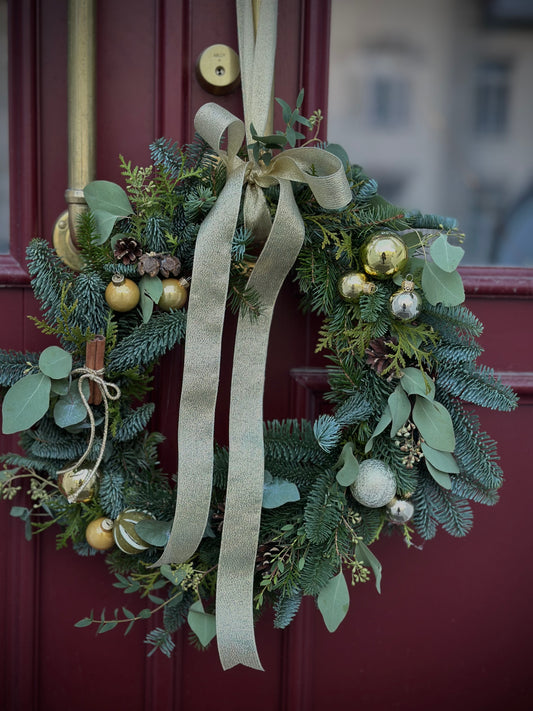 Elegant Christmas wreath with golden ornaments and ribbon on a red door, combining natural elements and festive charm | Элегантный рождественский венок с золотыми украшениями и лентой на красной двери, объединяющий природные элементы и праздничное очарование | Elegant Christmas wreath with gold accents and greenery, perfect for holiday decor.