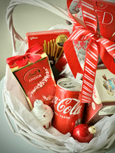 Load image into Gallery viewer, White basket with : Lindt candies, Coca Cola, Yoga tea, “Red” chocolate, cookies, Little Santa, designed post card 
