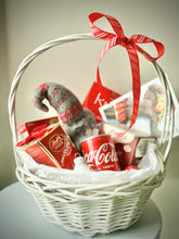 Load image into Gallery viewer, White basket with : Lindt candies, Coca Cola, Yoga tea, “Red” chocolate, cookies, Little Santa, designed post card 
