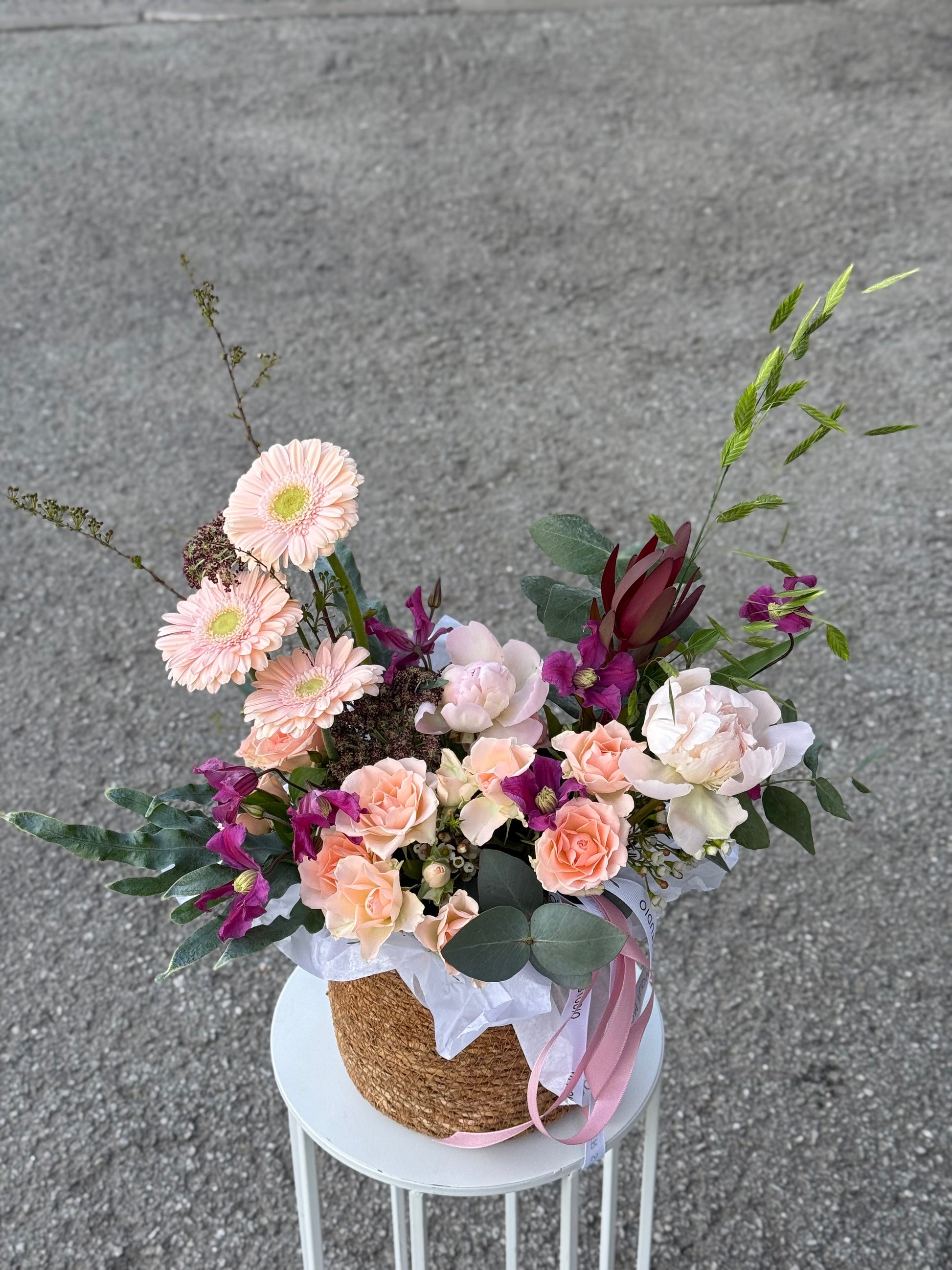 Signature flower arrangement in soft peach and blush tones, featuring spray roses, gerberas, eucalyptus, and seasonal blooms. A bubbly mix of elegance and cheer — like your favorite glass of prosecco in flower form. Comes in a natural basket with branded ribbon and care card.
