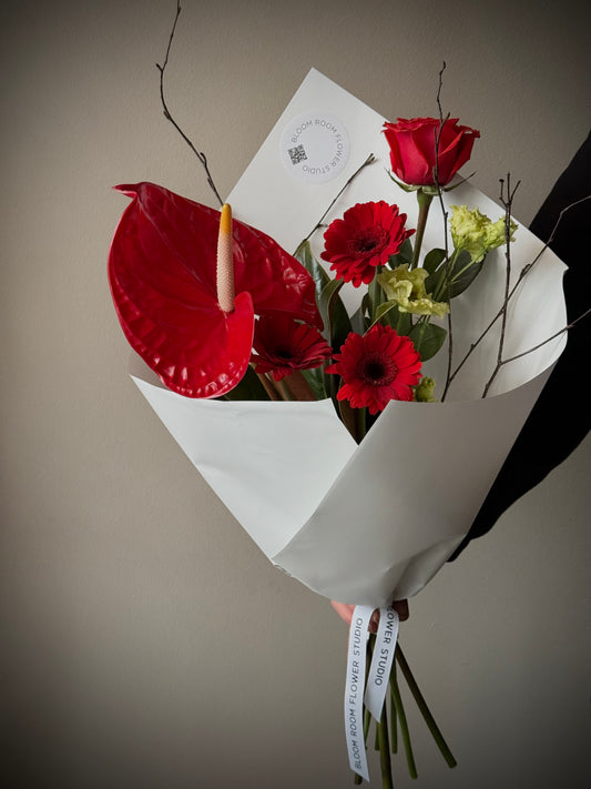 Punaste anthuriumi ja rooside koosseis, millel on gerberad ja eustoma, elegantses valges pakkes | Элегантный букет из красных антуриев и роз с герберами и эустомой в белой упаковке | Elegant bouquet of red anthuriums and roses with gerberas and eustoma in white wrapping – BloomRoom.ee, värsked lilled Tallinnas