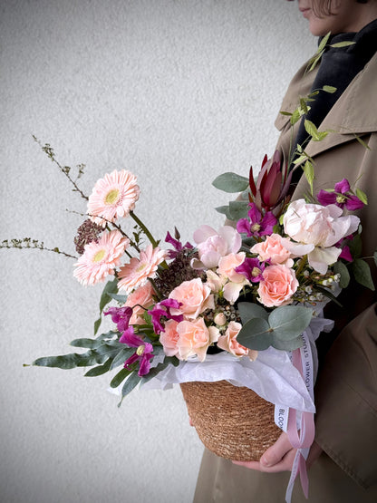 Signature flower arrangement in soft peach and blush tones, featuring spray roses, gerberas, eucalyptus, and seasonal blooms. A bubbly mix of elegance and cheer — like your favorite glass of prosecco in flower form. Comes in a natural basket with branded ribbon and care card.
