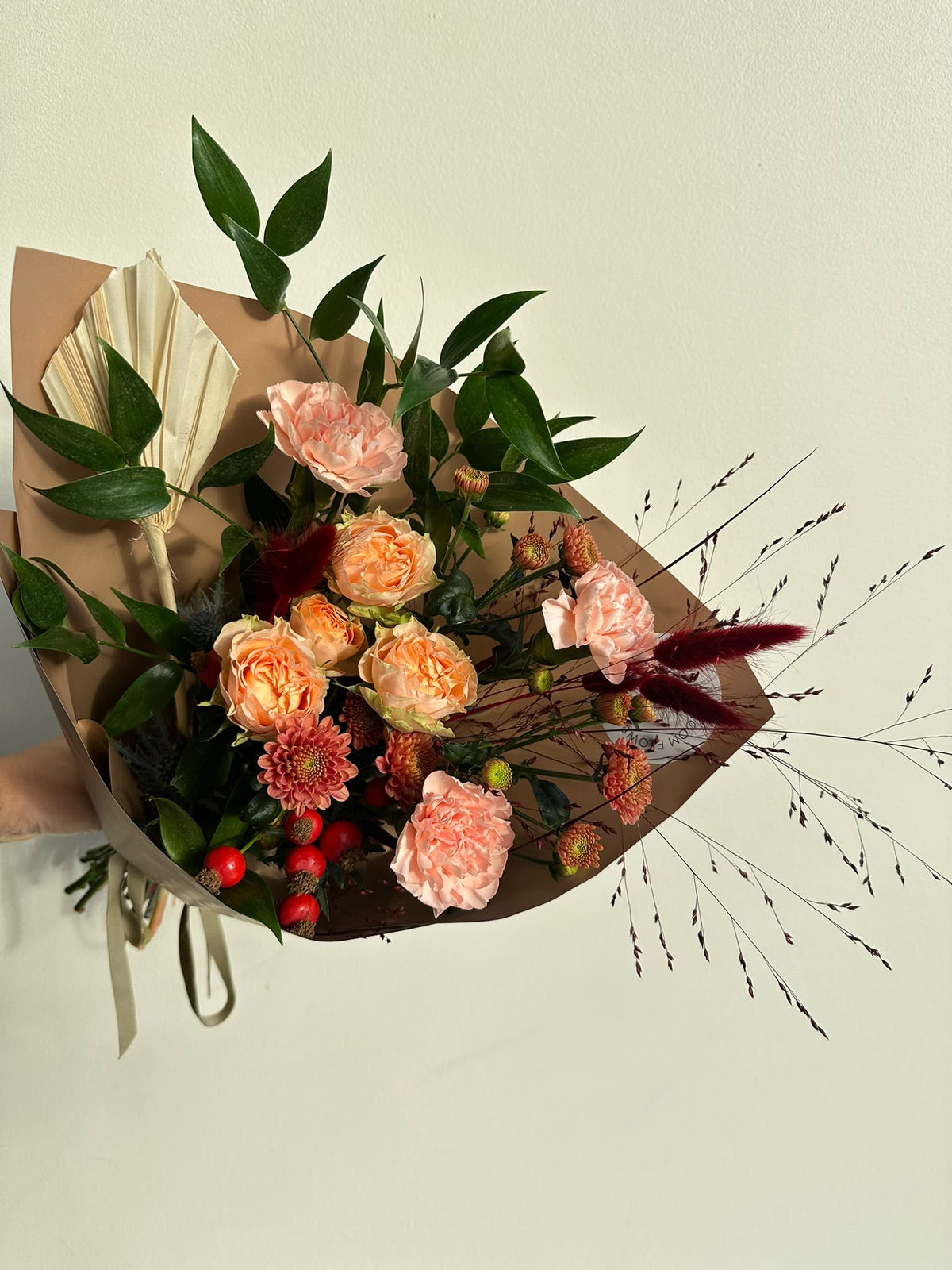 “Autumn Whisper” art bouquet with peach spray roses, carnations, copper chrysanthemums, rose hips and burgundy bunny tails in caramel wrapping