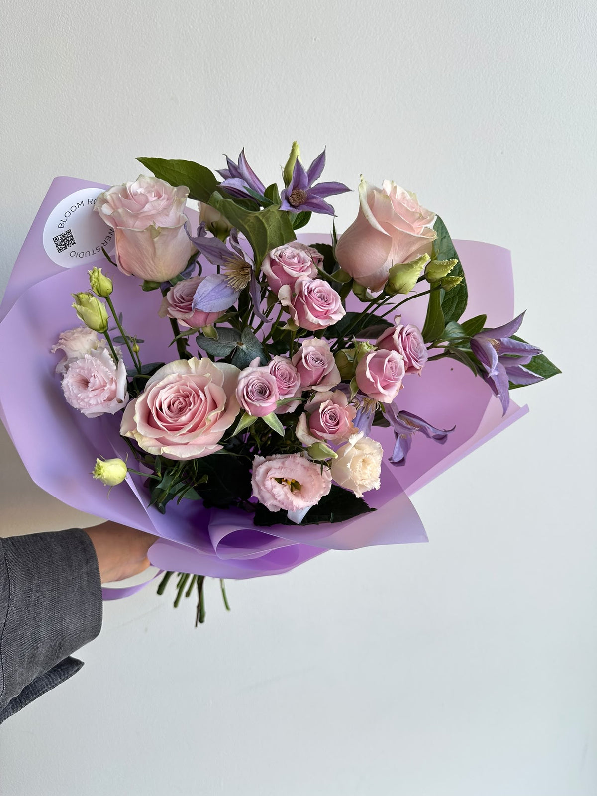 “Lavender Kiss” art bouquet with pink roses, spray roses, eustoma and purple clematis in lilac wrapping