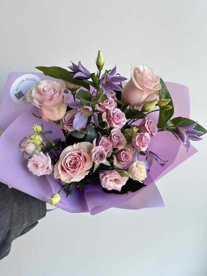 “Lavender Kiss” art bouquet with pink roses, spray roses, eustoma and purple clematis in lilac wrapping