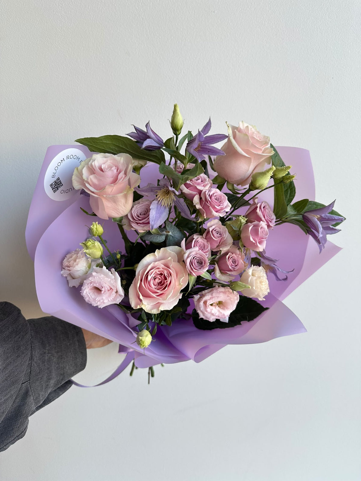 “Lavender Kiss” art bouquet with pink roses, spray roses, eustoma and purple clematis in lilac wrapping