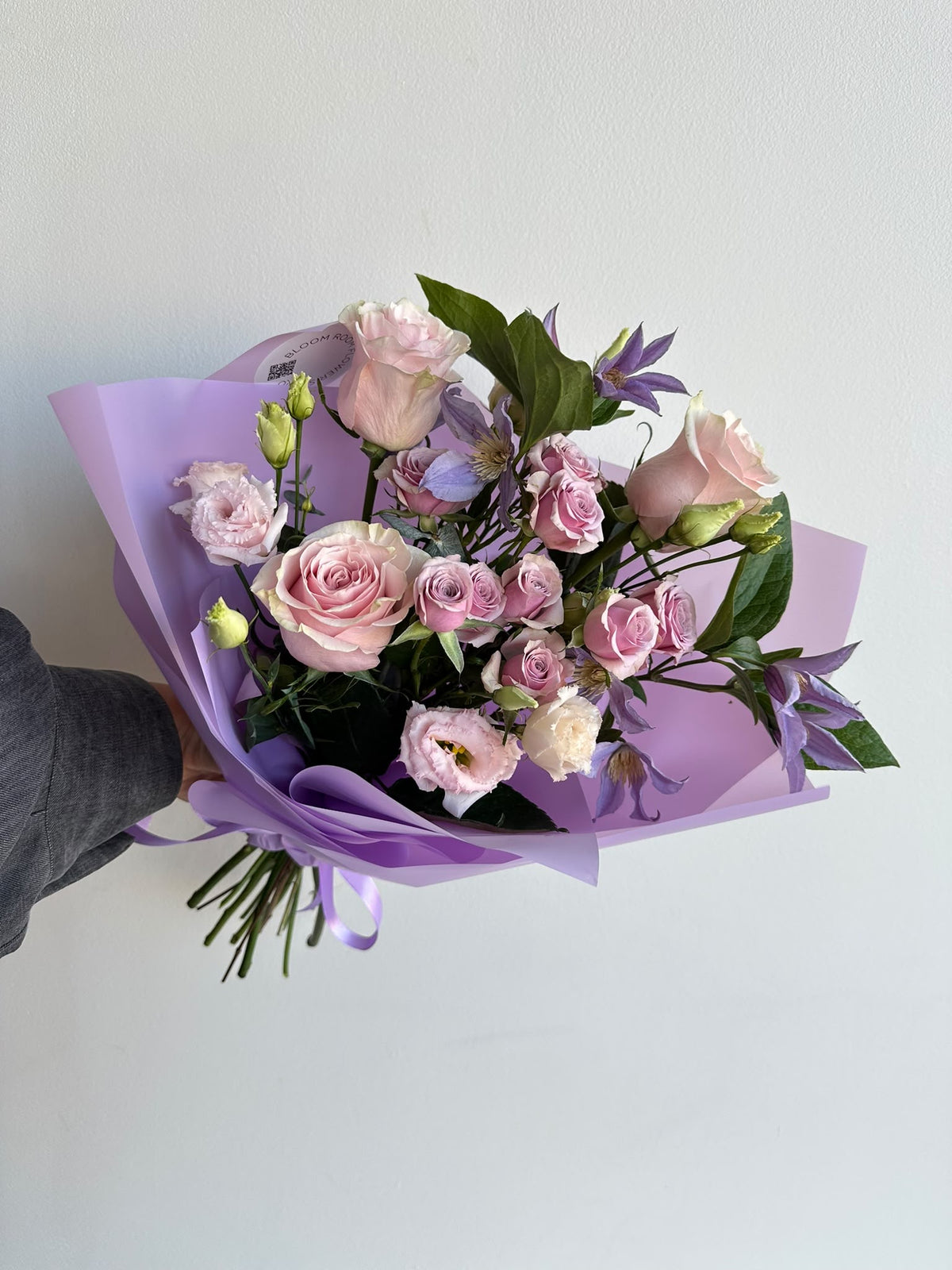 “Lavender Kiss” art bouquet with pink roses, spray roses, eustoma and purple clematis in lilac wrapping