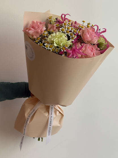 „Sweet Serenade“ floristi kimp roosade kobarrooside, roheliste nelkide, roosa nerine ja kummeliga kreemikas pakendis