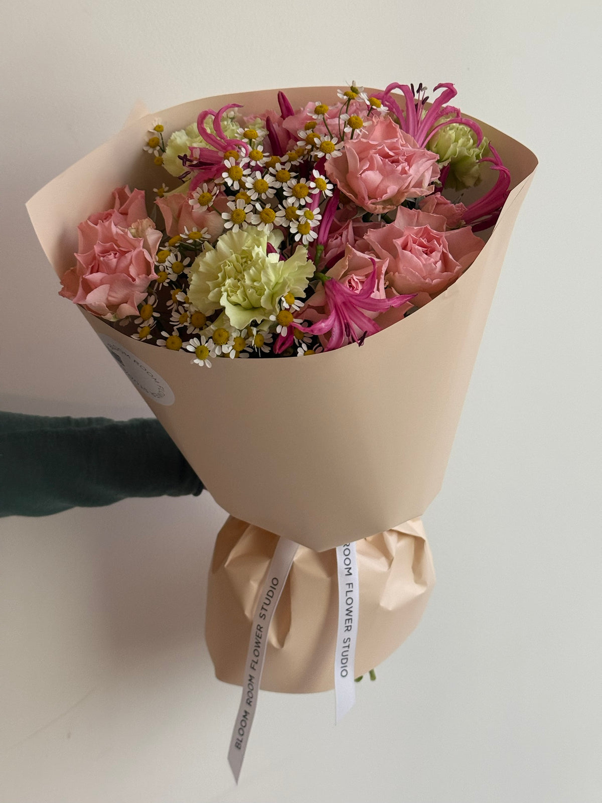 „Sweet Serenade“ floristi kimp roosade kobarrooside, roheliste nelkide, roosa nerine ja kummeliga kreemikas pakendis
