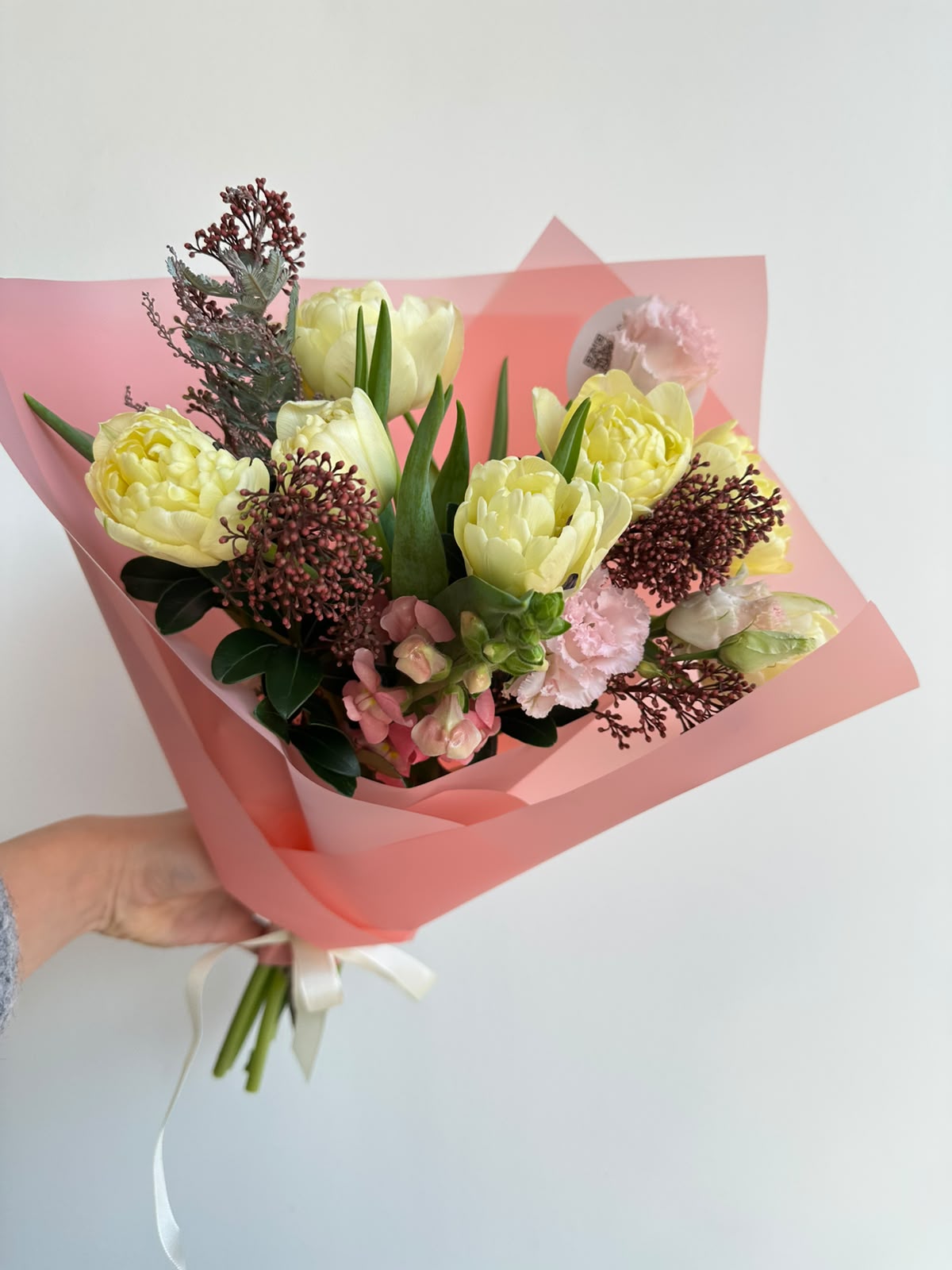 “Vanilla Romance” art bouquet with creamy peony tulips, burgundy skimmia, pink carnations and snapdragons in pink wrapping