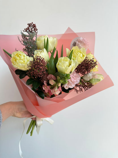“Vanilla Romance” art bouquet with creamy peony tulips, burgundy skimmia, pink carnations and snapdragons in pink wrapping
