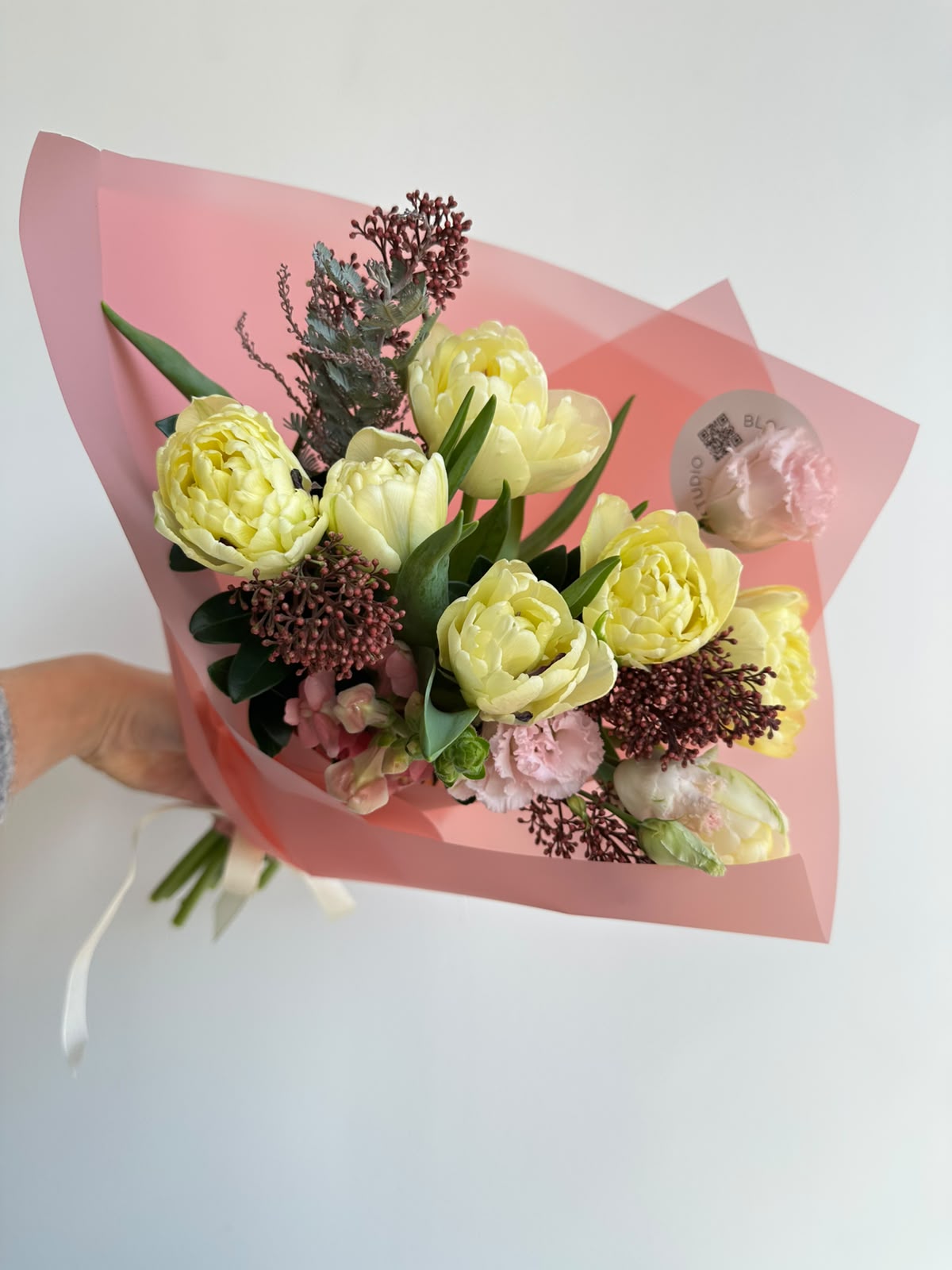 “Vanilla Romance” art bouquet with creamy peony tulips, burgundy skimmia, pink carnations and snapdragons in pink wrapping